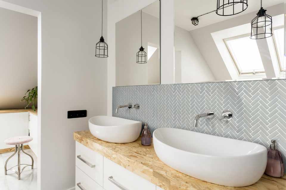 gray tile inlaid in herringbone pattern as backsplash in contemporary bathroom with double sink